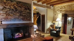A cozy living room with a fireplace, a dining table, and a comfortable seating area. - DOMAINE DE LABROUSSE (Agonac)
