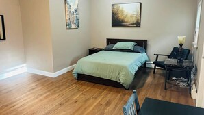 A bedroom with a bed, a nightstand, a lamp, and a chair. - Large room with private bathroom near Whole Foods (Providence)