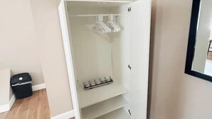 A small, open closet with shelves and hanging space, a black trash bin, and a mirror on the wall. - Large room with private bathroom near Whole Foods (Providence)