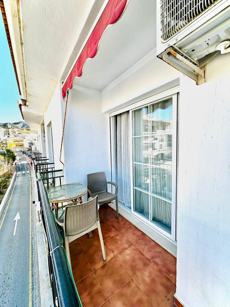 Un balcone con tavolo e sedie, un'ampia finestra e vista sulla strada.