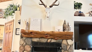 A stone fireplace with a mounted deer skull above it, a wooden mantel, and a sign titled "Cabin Rules" beside the fireplace. - Private 3-bedroom Cabin in charming Show Low within Torreon (Show Low)