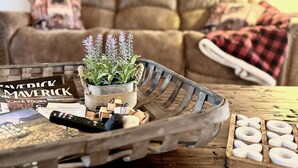 A cozy living room with a brown sofa, a small potted plant, a tray with wooden blocks, and a printed magazine. - Private 3-bedroom Cabin in charming Show Low within Torreon (Show Low)