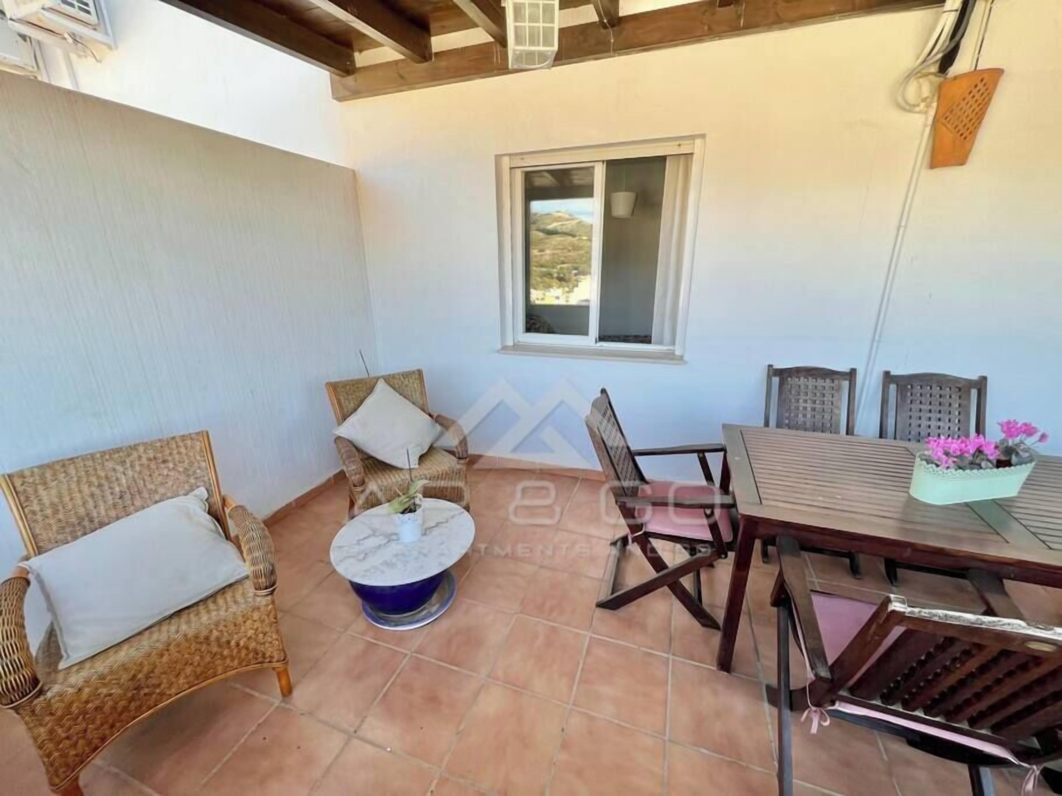 A patio area with wicker furniture, a round table, and a window.