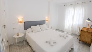 Ett välordnat hotellrum med en stor säng, sänglampor, ett litet runt bord och ett skrivbord med en lampa.