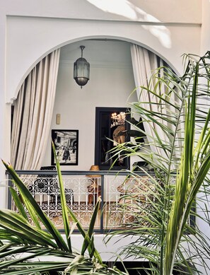 An arched entrance with a hanging lantern, a framed picture, and a view of the interior through a window. - Riad Instant T (Marrakech)