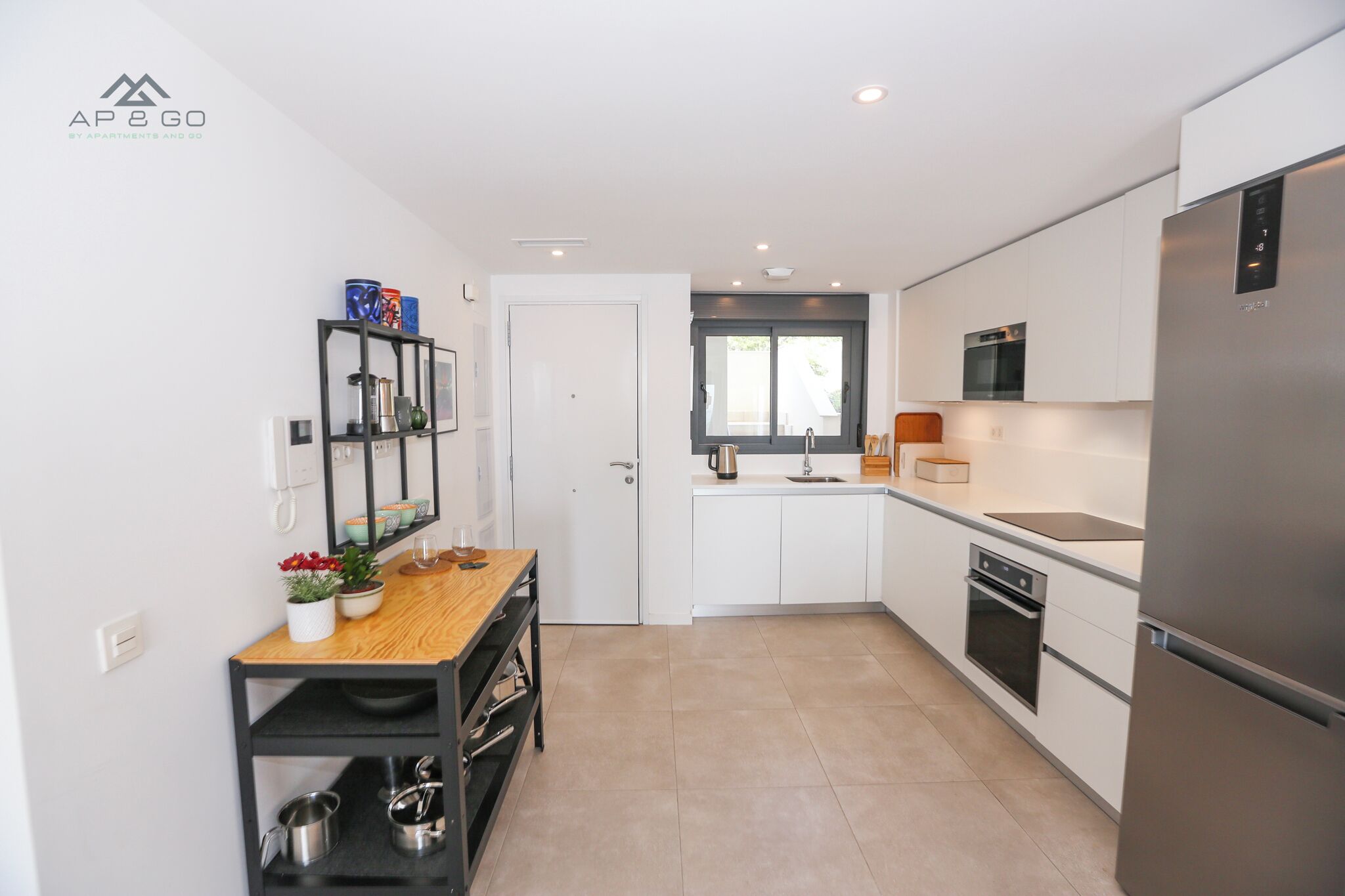 Una cocina moderna con armarios blancos, un refrigerador de acero inoxidable y una encimera de madera.