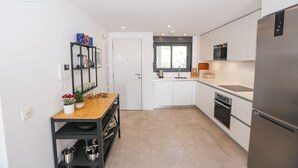 Une cuisine moderne avec des meubles blancs, un réfrigérateur en acier inoxydable et un plan de travail en bois.