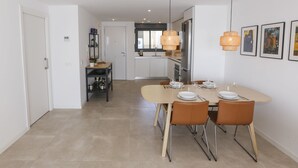 Une cuisine moderne avec un coin repas, comprenant un grand îlot central, des appareils en acier inoxydable et un luminaire suspendu.