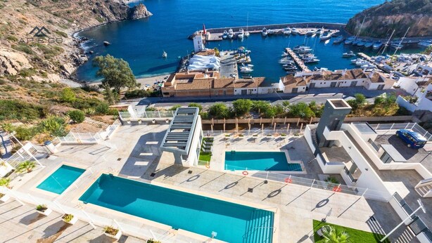 Un espace piscine sur le toit, comprenant deux piscines, un parking et une vue sur un port de plaisance avec des bateaux.