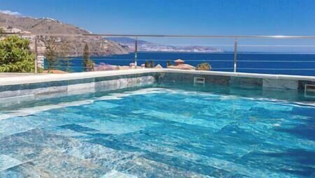 A clear blue pool with a view of the sea and a mountainous landscape in the background. - Blue Villa Rest & Pool (Velilla-Taramay)