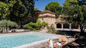 A poolside area with a lounge chair and a person relaxing. - Paradise in Provence: Chateau du Jonquier (Mazan)