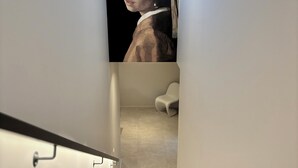 A narrow hallway with a staircase leading to a room.