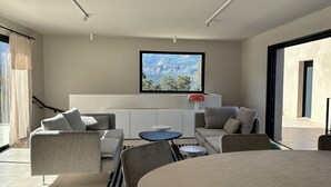 A modern living room with a sofa, chairs, a coffee table, and a view of mountains through a large window.
