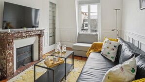 A living room with a fireplace, a sofa, a coffee table, and a television. - Arc de Triomphe - Lauriston 1bdr by B'Your Home (Paris)