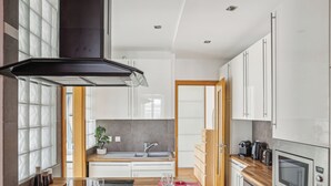 A modern kitchen with white cabinets, a built-in oven, and a wooden countertop. - Arc de Triomphe - Lauriston 1bdr by B'Your Home (Paris)