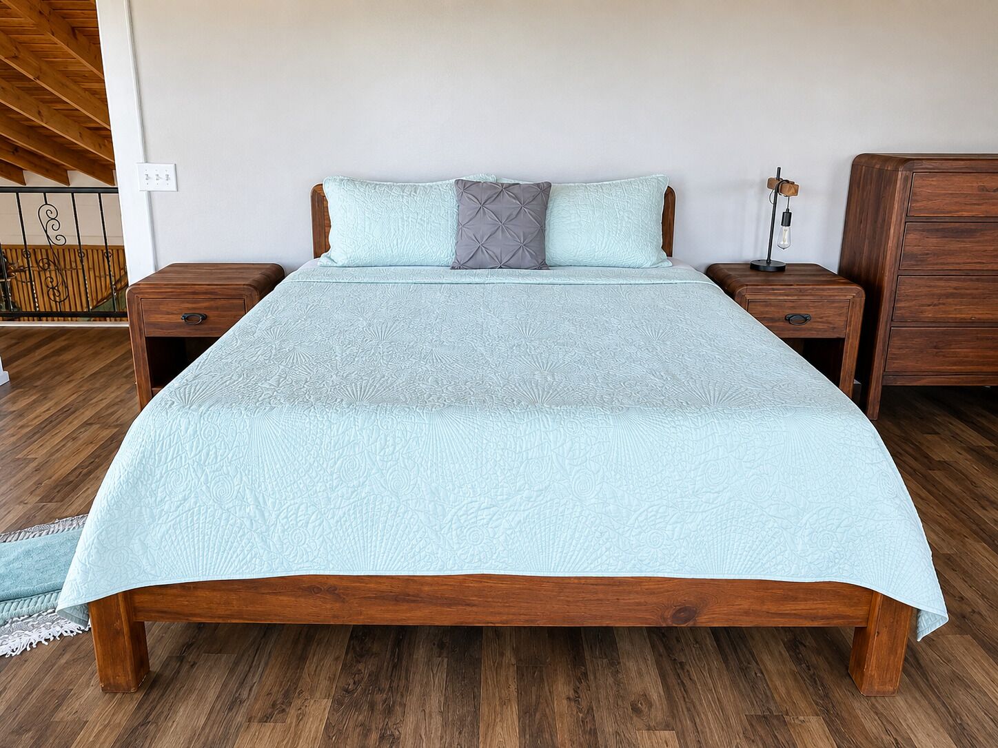 Ein Bett mit gemustertem Überwurf, zwei Nachttische, ein Holz-Kopfteil und ein Nachttisch mit Lampe.