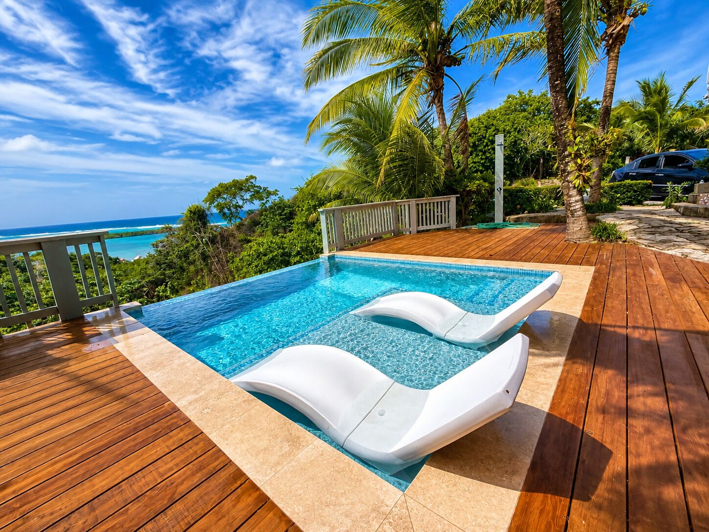 A swimming pool with a wooden deck and a view of the ocean.