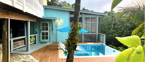 Uma casa com piscina, deck de madeira e fachada azul.