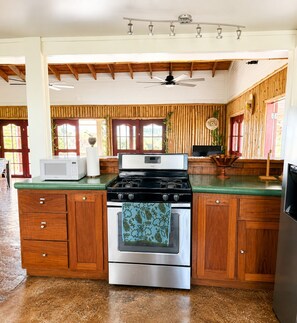 A kitchen with a stainless steel stove, wooden cabinets, and a green countertop.