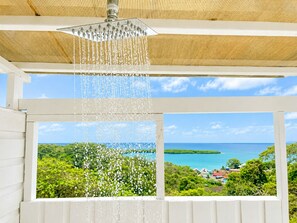 A shower with a view of a coastal landscape.