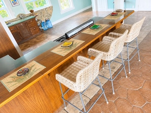 A long wooden bar with barstools and a built-in grill.