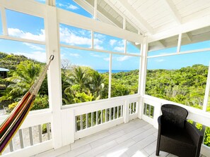 A room with large windows, a hammock, and a wicker chair.