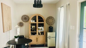A dining area with a round table, chairs, a cabinet with glass doors, and a ceiling fan.