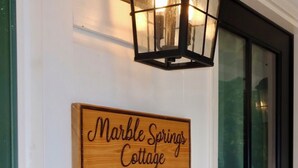 A wooden sign with the text "Marble Springs Cottage" mounted on a white wall.