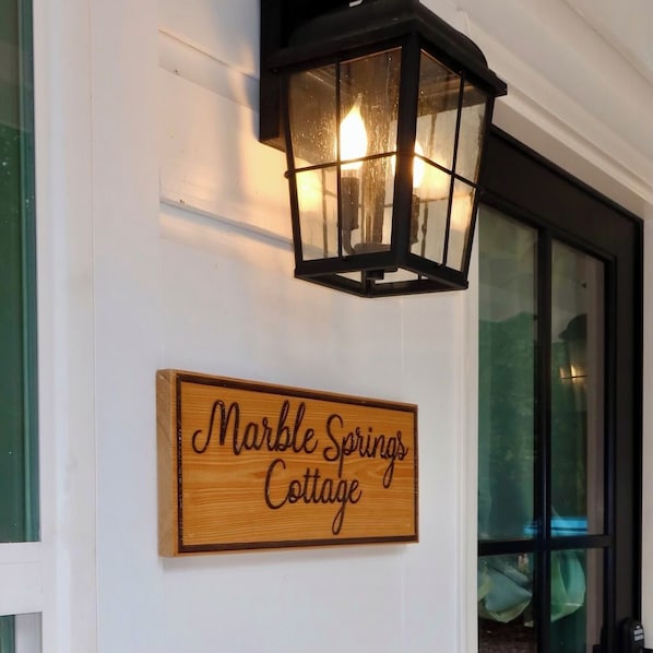 A wooden sign with the text "Marble Springs Cottage" mounted on a white wall.