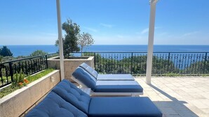 A covered outdoor seating area with three lounge chairs and a view of the sea. -  Casa Oliva Villas with Private Heated Pools and Guest Apartments-No Pool Access (Petrovac)