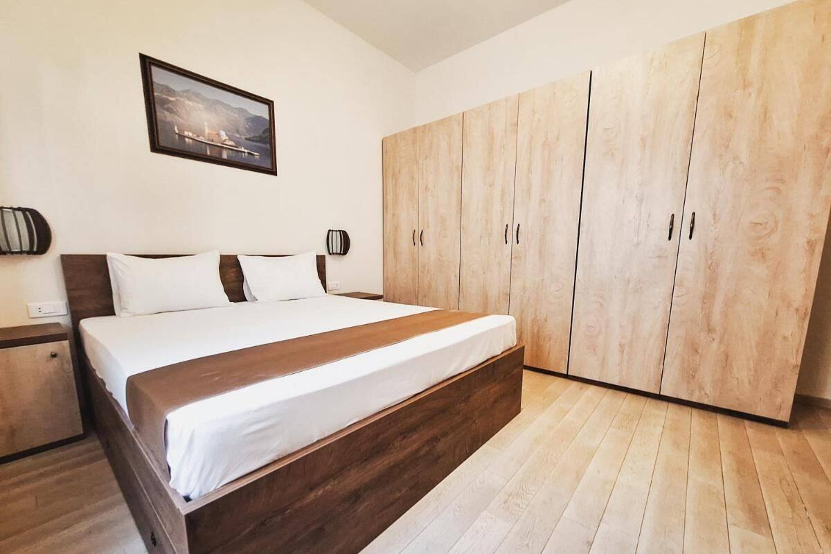 Een slaapkamer met een houten bed, een kledingkast en een lijst met een afbeelding aan de muur.