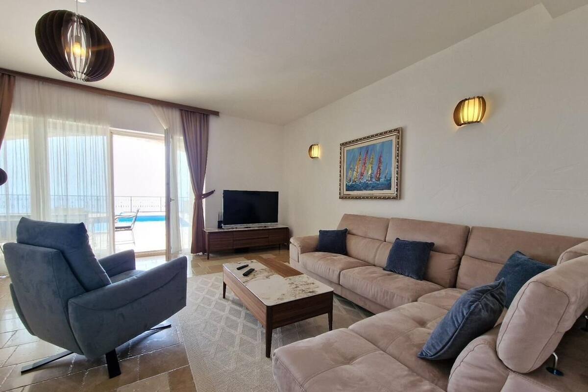 Een moderne woonkamer met een bank, een televisie en een schilderij aan de muur.