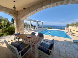 A poolside area with a table and chairs, a pool, and a view of the sea. -  Casa Oliva Villas with Private Heated Pools (Petrovac)