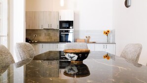 A modern kitchen with white cabinets, a black countertop, and a marble dining table with a decorative bowl centerpiece. -  Casa Oliva Villas with Private Heated Pools and Guest Apartments-No Pool Access (Petrovac)