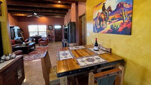 A dining area with a wooden table, chairs, and a painting of a horse and cactus on the wall.