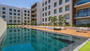 Un bâtiment moderne doté d’une piscine, d’un espace extérieur aménagé et d’une pelouse bien entretenue.