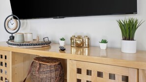 A wooden console table with a clock, a camera, and potted plants. - Casa Azul Memphis Midtown Cooper Young (Memphis)
