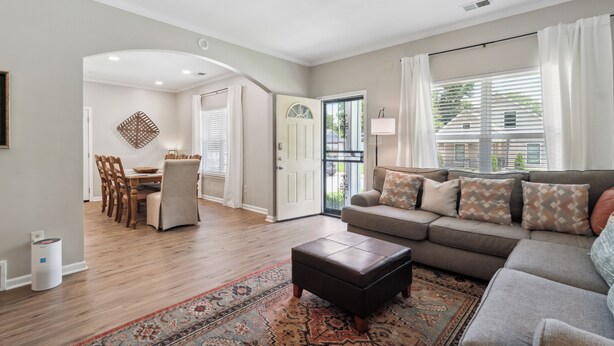 A living room with a sofa, ottoman, and a dining area with chairs and a table. - Casa Azul Memphis Midtown Cooper Young (Memphis)