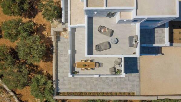 Luchtbeeld van een modern huis met een patio, voorzien van een eettafel, twee banken en een kleine ronde tafel.