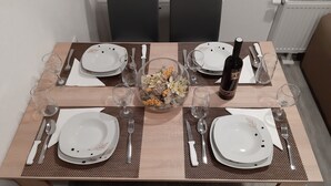 A dining table set for four with white plates, cutlery, and wine glasses. A decorative bowl with flowers is placed in the center. - Charming 2-bedroom apartment 2 with WiFi, AC in delightful Plitvice Lakes (Plitvice lakes)
