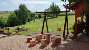 An outdoor play area with swings, a climbing structure, and a view of a green field. - Charming 2-bedroom apartment 2 with WiFi, AC in delightful Plitvice Lakes (Plitvice lakes)