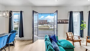Een moderne woonkamer met een bank, stoelen, een eettafel en uitzicht door een glazen deur.