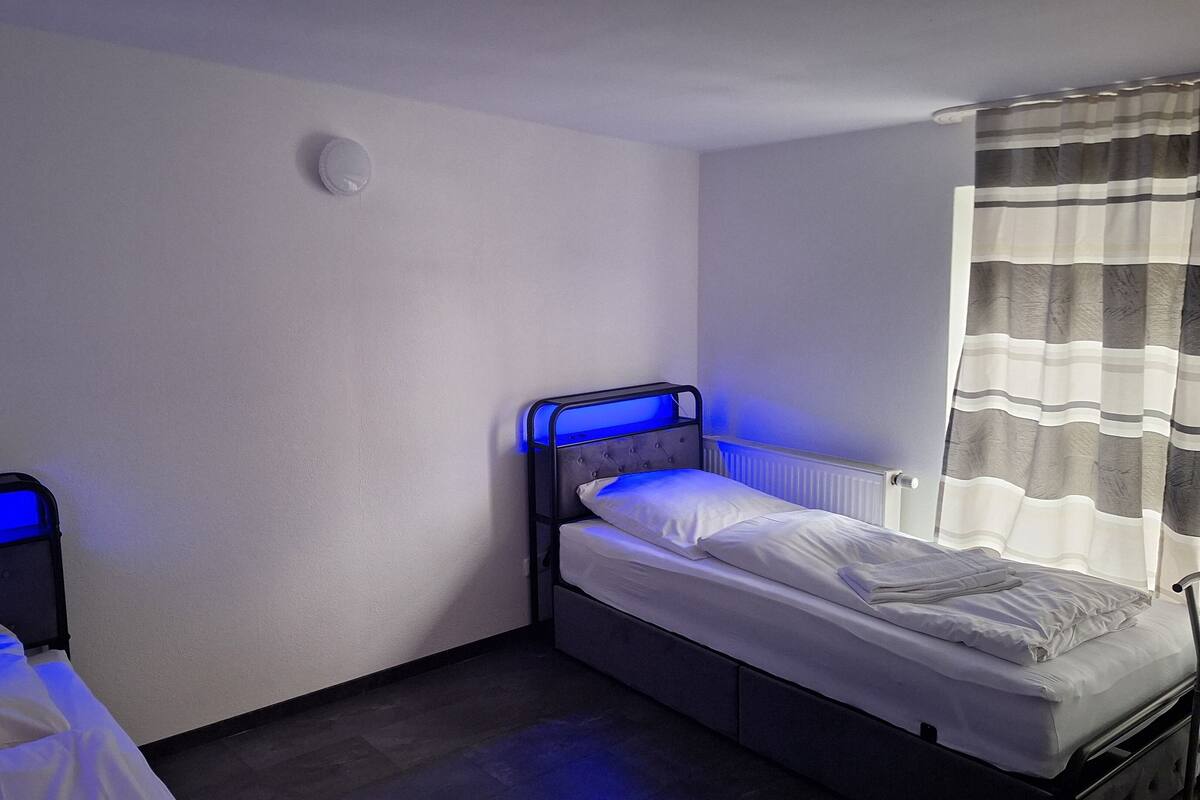 Ein kleines Hotelzimmer mit zwei Betten, eines mit Kopfteil und das andere mit Fußteil.