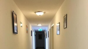 A hotel hallway with framed pictures on the walls, a tiled floor, and a ceiling light. - Pension Alis (Augsburg)