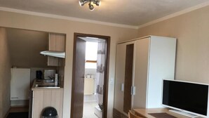 A compact room with a kitchenette, a TV, a desk, and a chair. - Pension Alis (Augsburg)