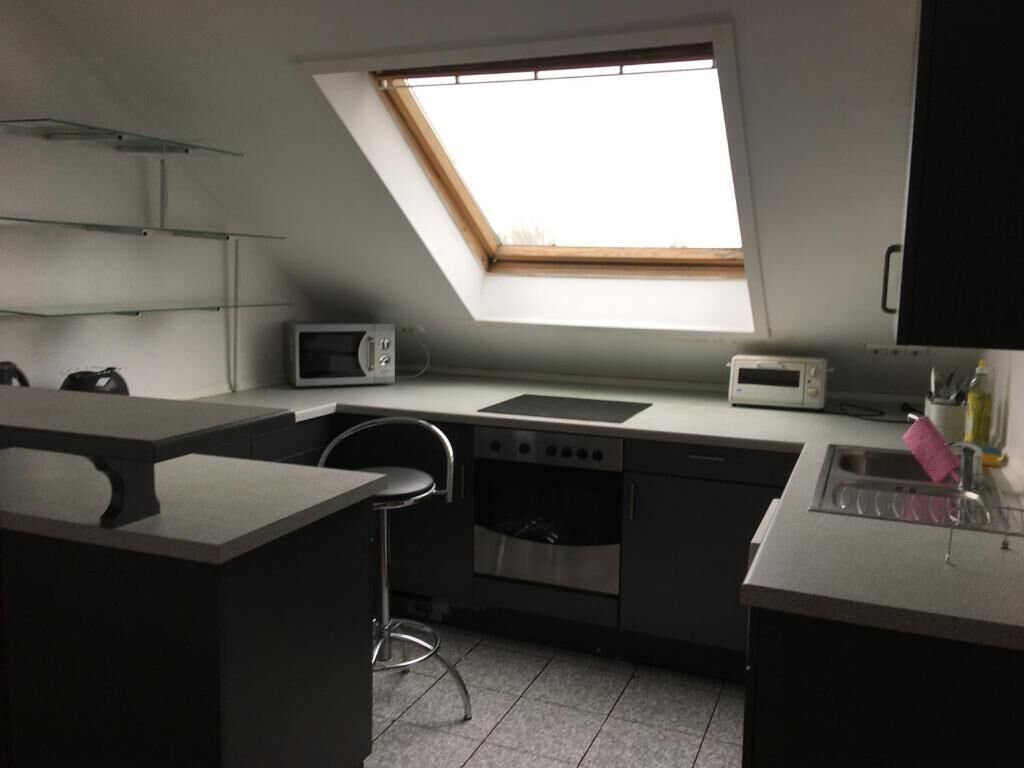 Une cuisine compacte dotée d’une lucarne, d’un four à micro-ondes, d’une cuisinière et d’un évier.