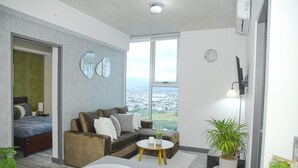 A modern living room with a sofa, a coffee table, and a view of the city through large windows. - Secrt Sabana 2BR · Skyline View · High Floor · Pool & Gym · Apt 2810 (Mata Redonda)
