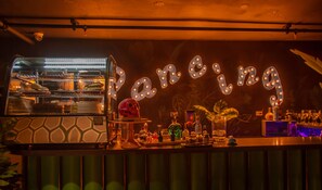 A bar area with a neon sign spelling "Dancing," a well-lit oven, and various bar items. - Secrt Sabana 2BR · Spacious Living · Pool & Gym · Parking ·  Apt 2209 (Mata Redonda)