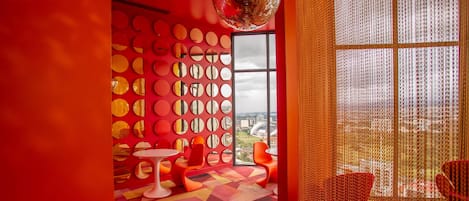 A vibrant room with a geometric patterned carpet, a disco ball, and a wall adorned with circular mirrors.