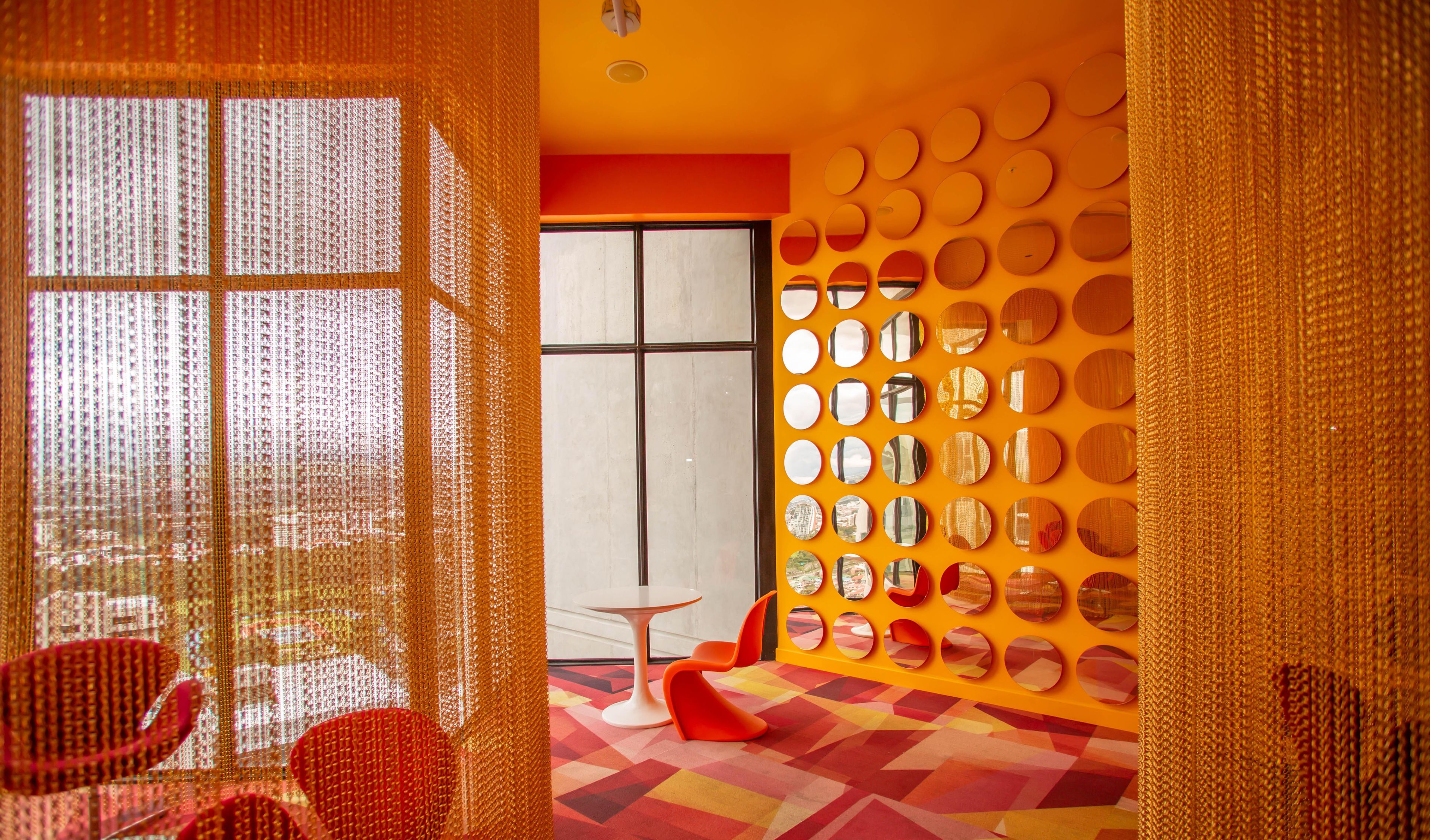 A modern interior with a geometric patterned floor, a large window, and a wall decorated with circular mirrors.